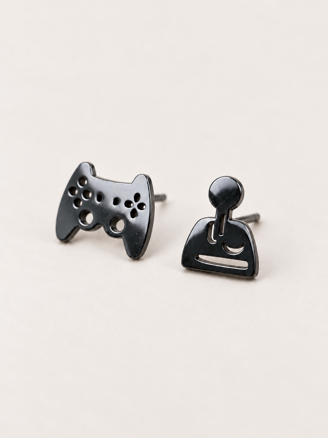 black Game Controller and Joystick Earrings shown angled on a warm neutral background