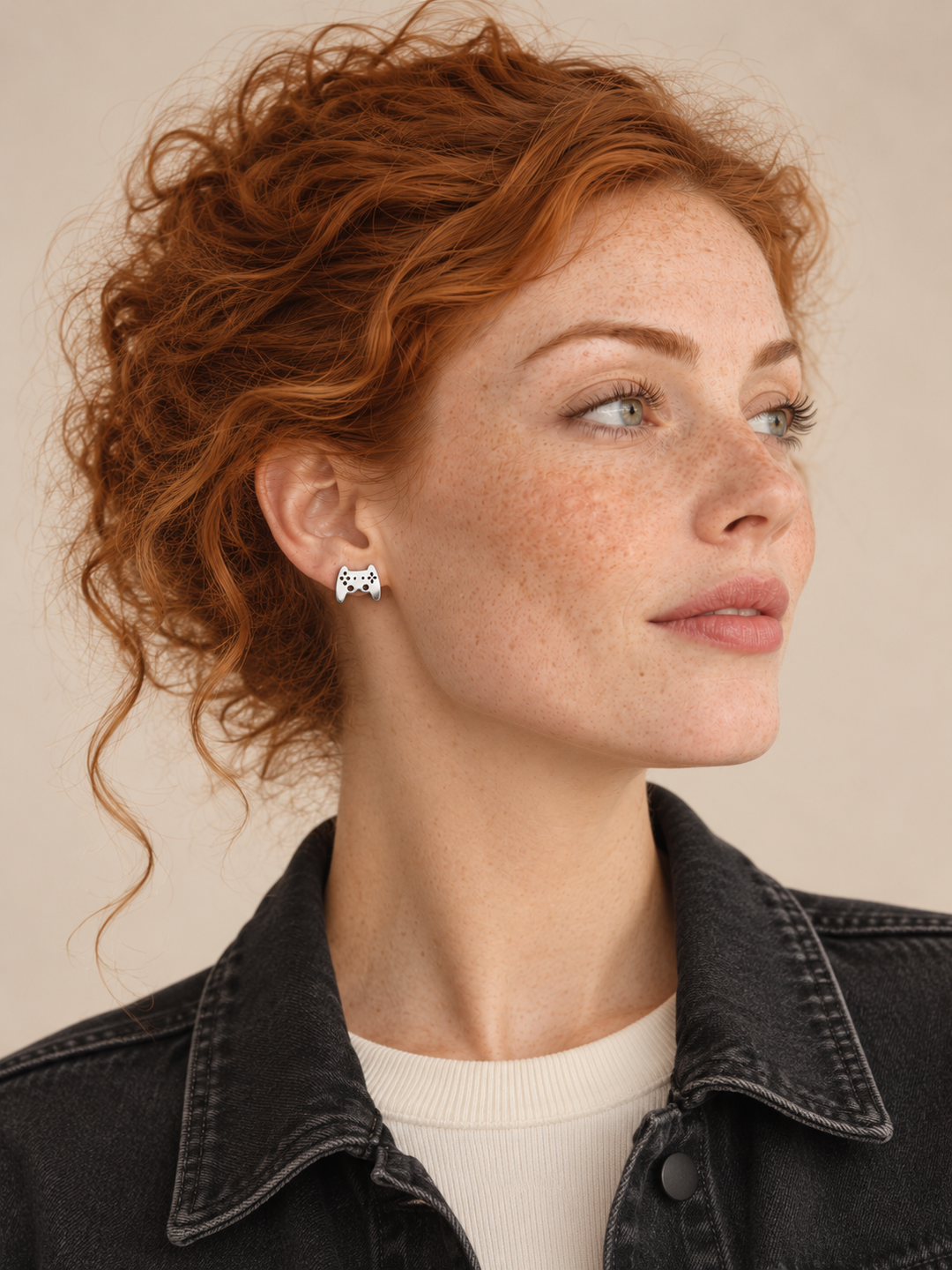 Silver game controller stud on the viewer-left ear worn by a model