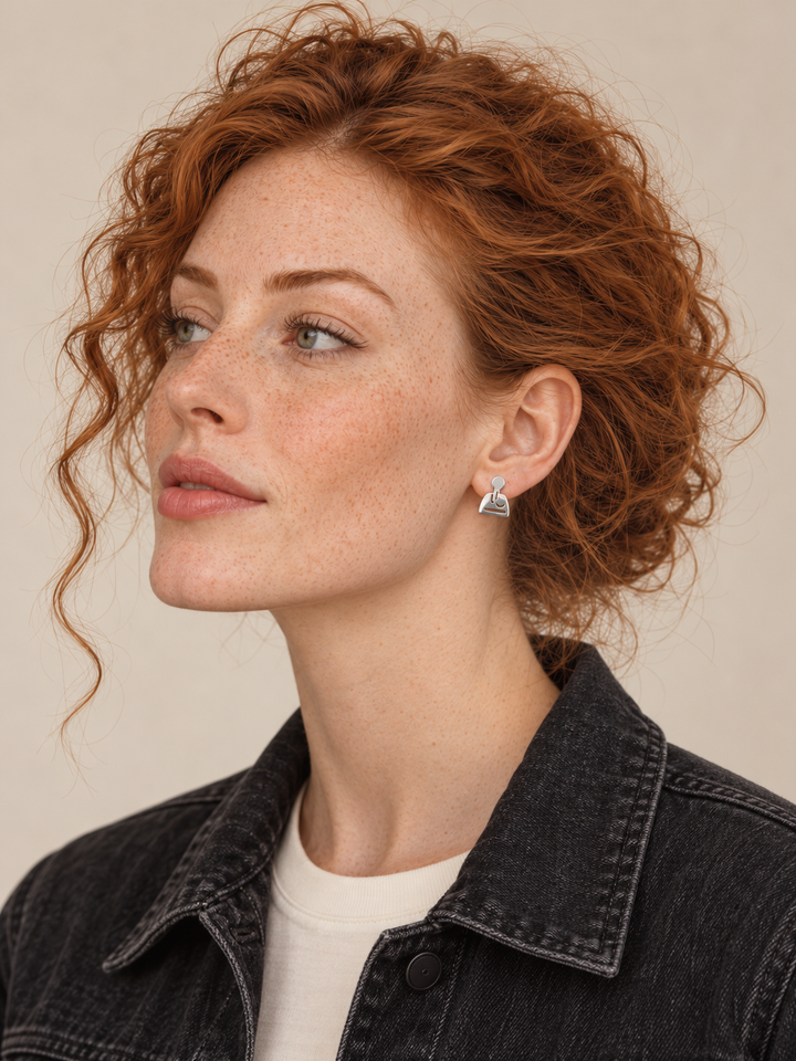 Silver joystick stud on the viewer-right ear worn by a model