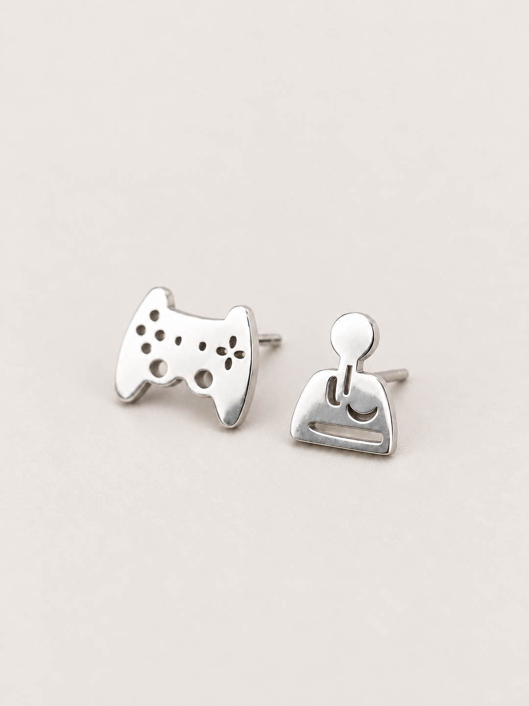 silver Game Controller and Joystick Earrings shown angled on a warm neutral background