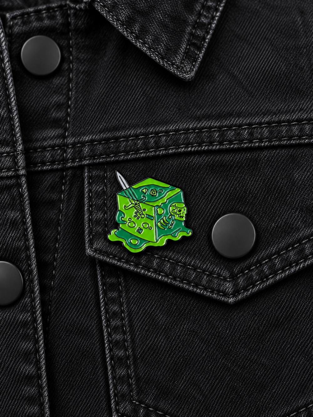 Gelatinous Cube Dungeon Pin displayed on a black denim jacket beside a matte black button