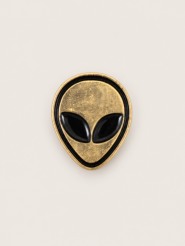 Gold Alien Head Pin shown on a warm neutral background