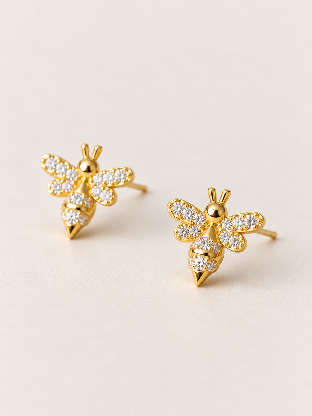 Gold Crystal Bee Stud Earrings shown angled on a warm neutral background