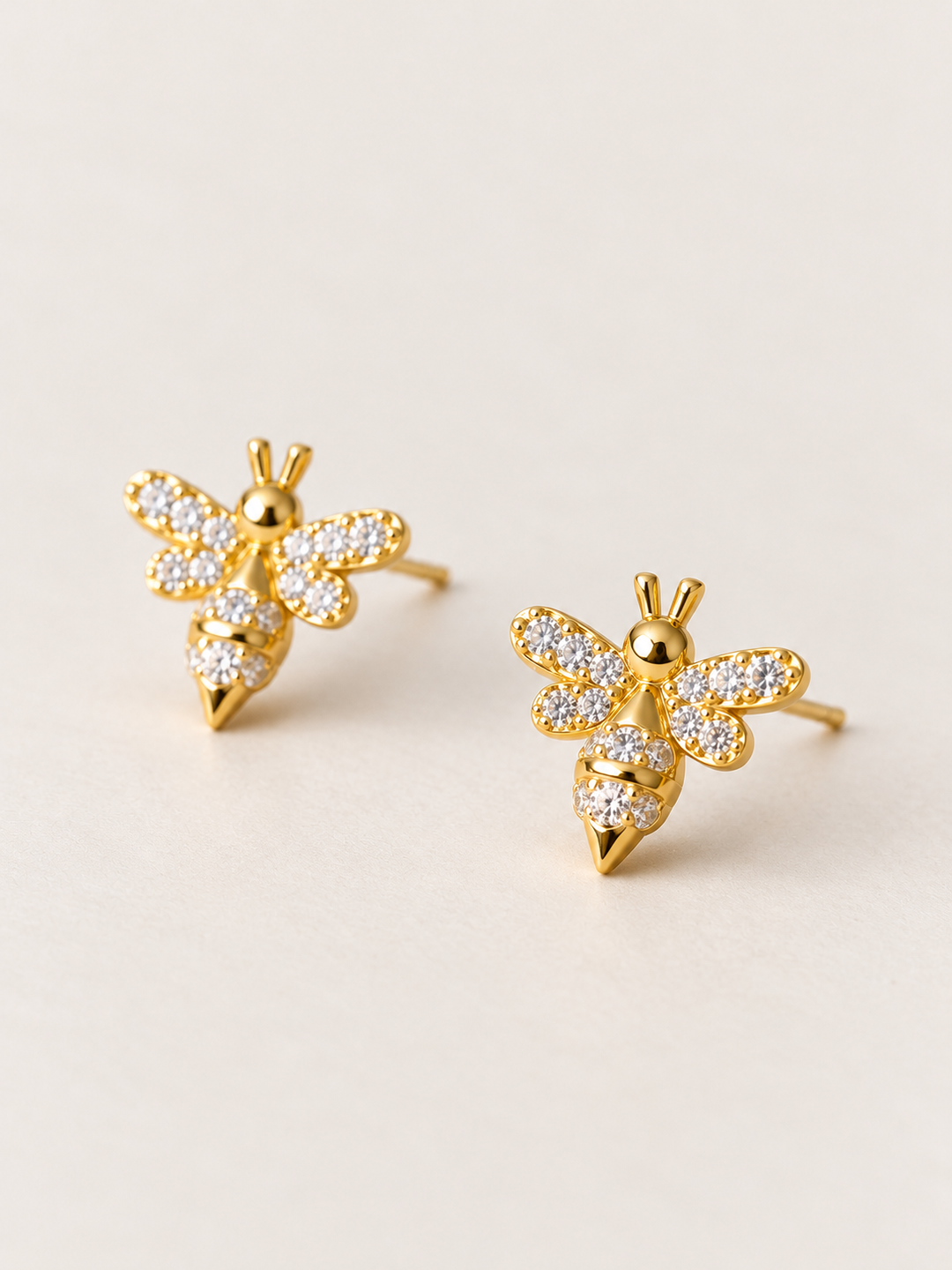 Gold Crystal Bee Stud Earrings shown angled on a warm neutral background