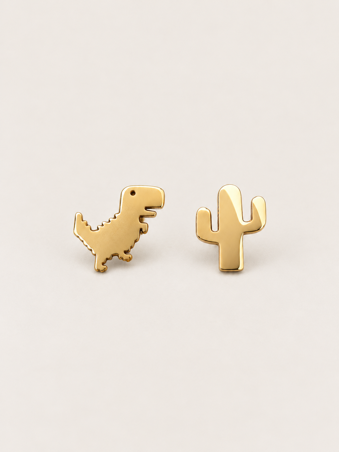 Gold Dinosaur and Cactus Stud Earrings shown on a warm neutral background