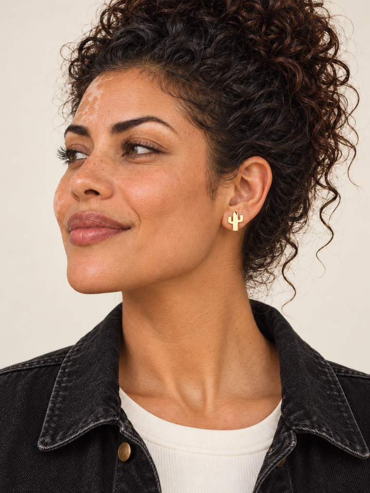 Gold cactus stud earring worn on viewer-right ear