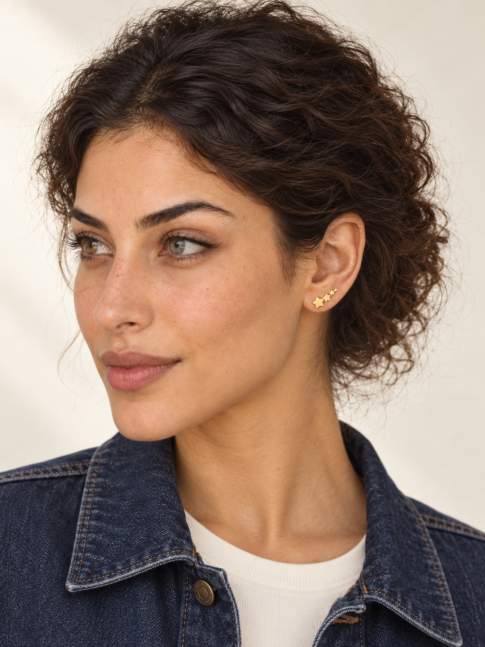 Gold Graduated Star Stud Earrings worn on a model's viewer-right ear