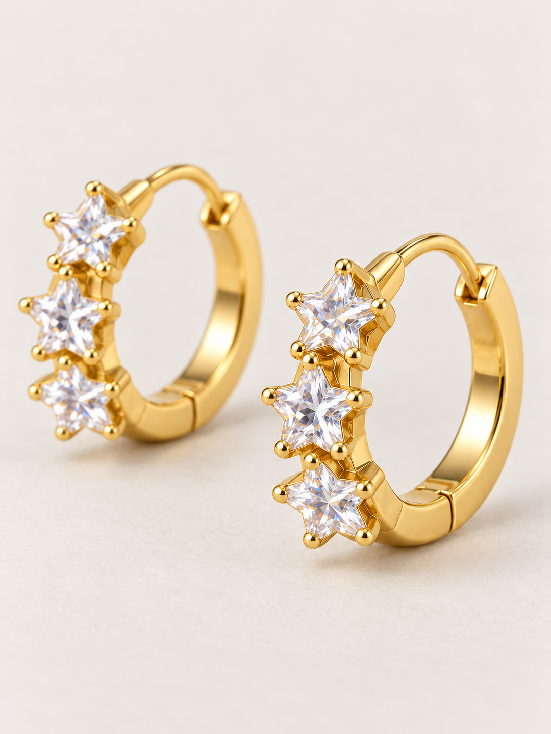 Gold Huggie Earrings shown angled on a warm neutral background