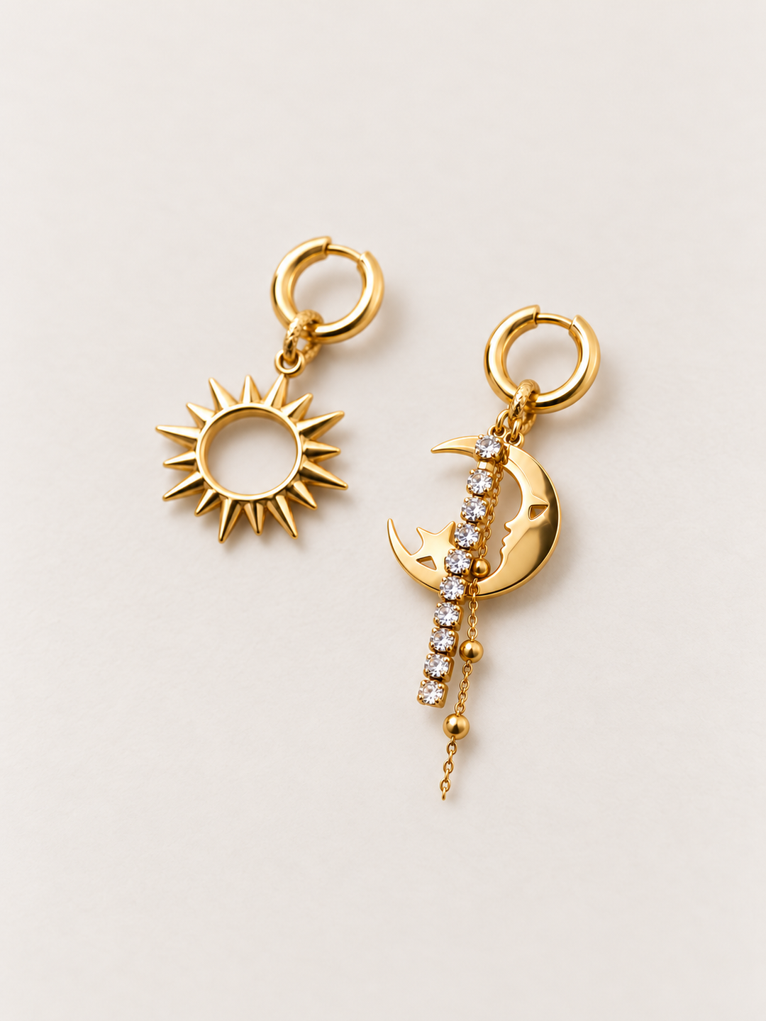 Gold Sun and Moon Drop Earrings shown angled on a warm neutral background