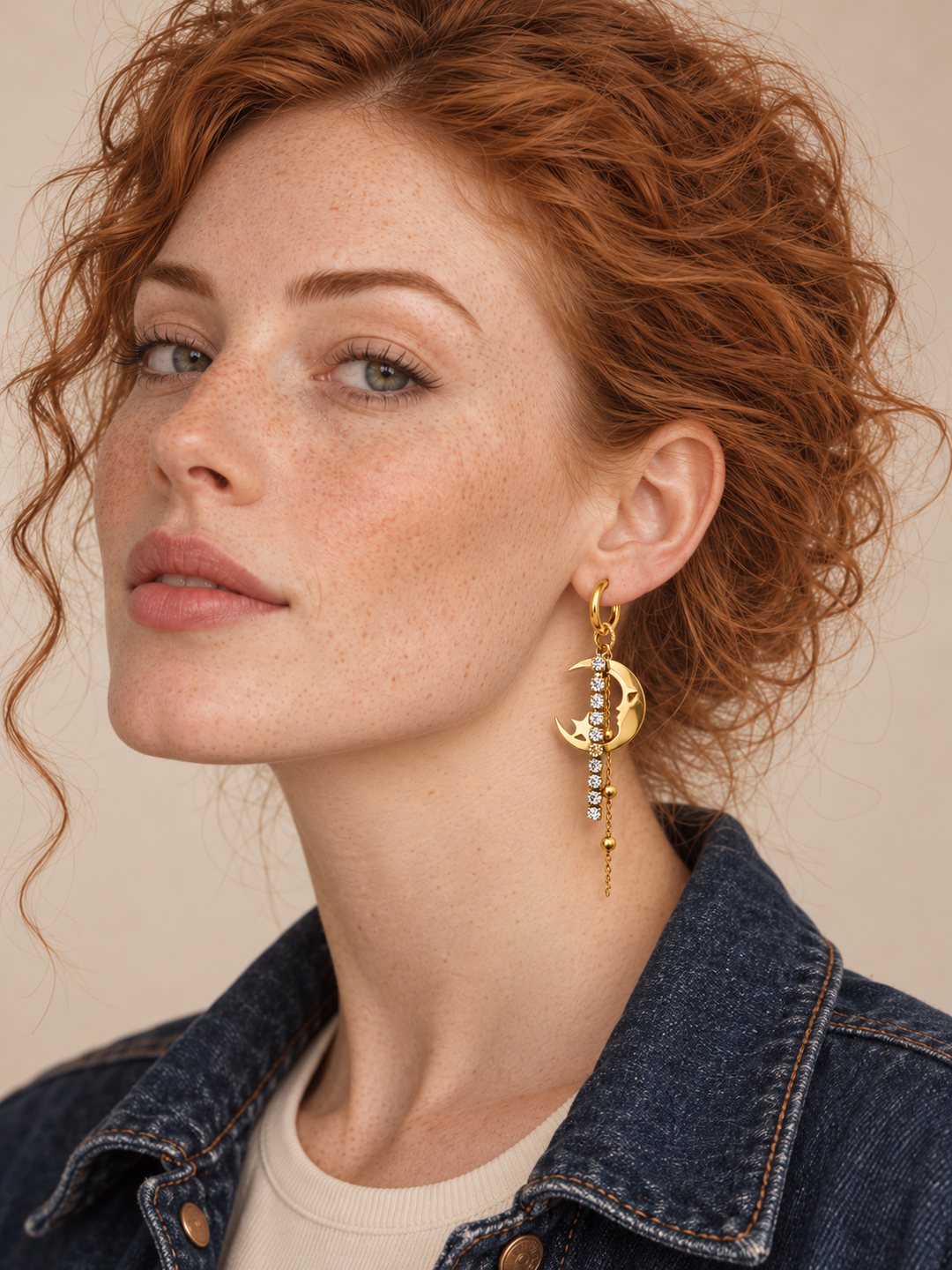 Gold crescent moon earring with crystals and beaded chain worn on the viewer-right ear