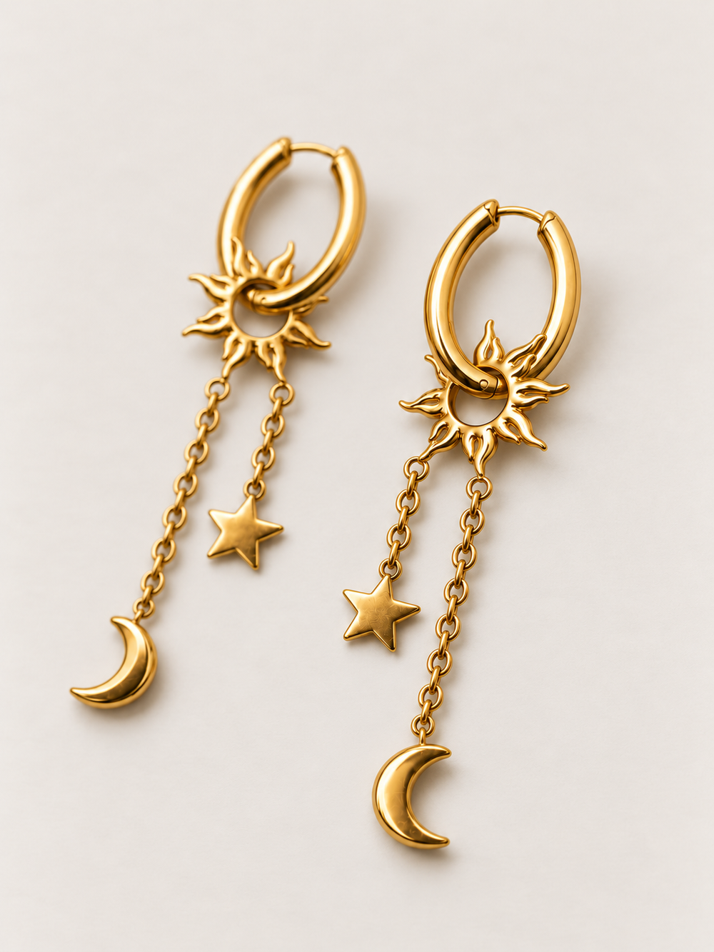 Gold Sun Moon Star Hoop Earrings shown angled on a warm neutral background