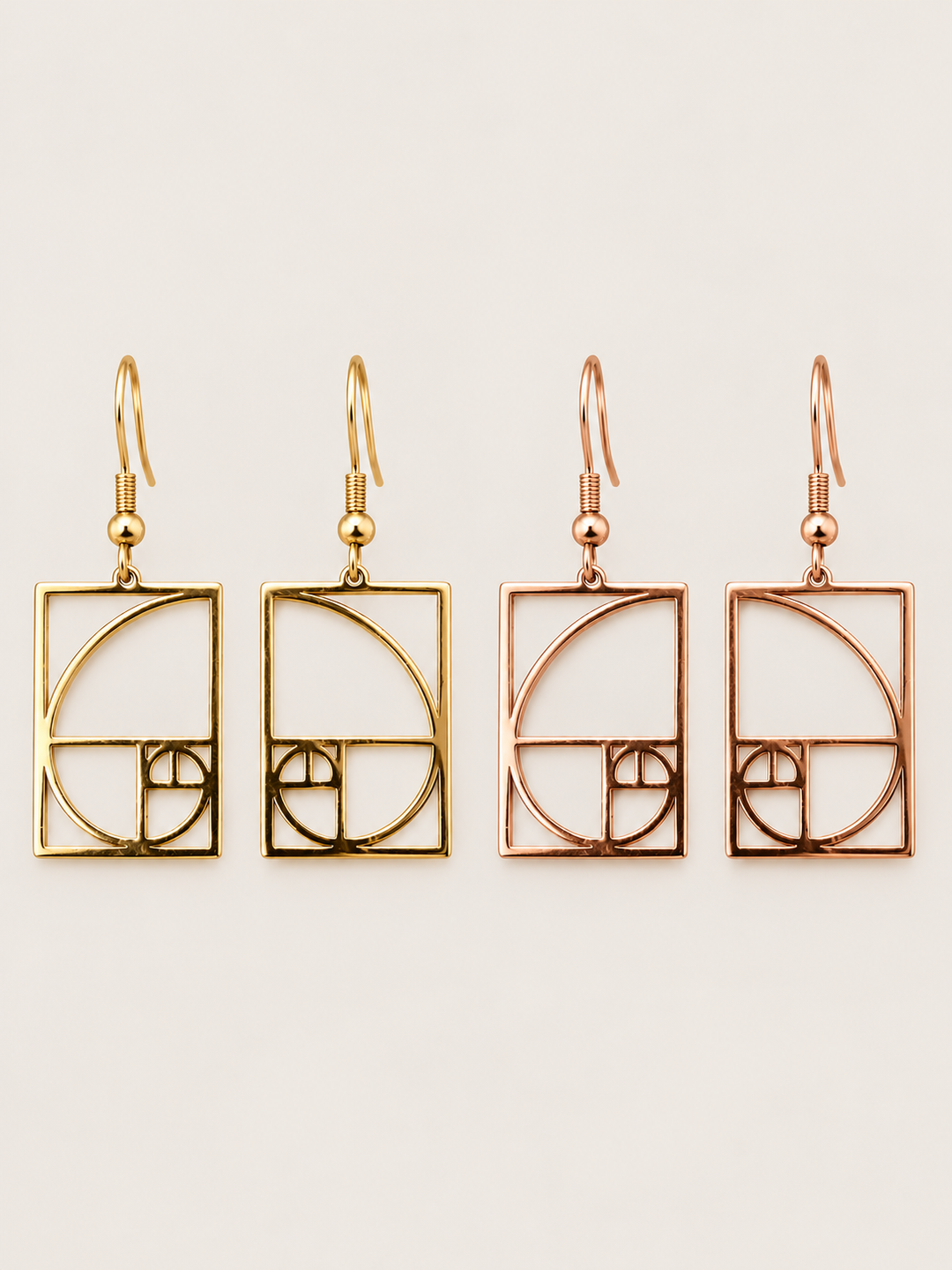 Gold and rose gold Golden Ratio Spiral Drop Earrings shown on a warm neutral background