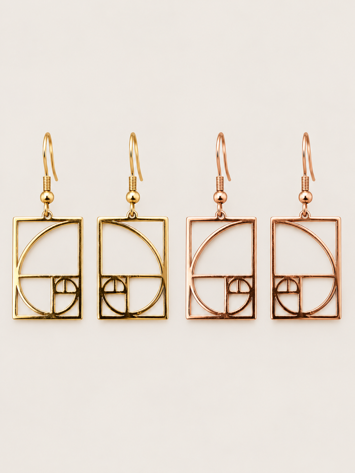 Gold and rose gold Golden Ratio Spiral Drop Earrings shown on a warm neutral background