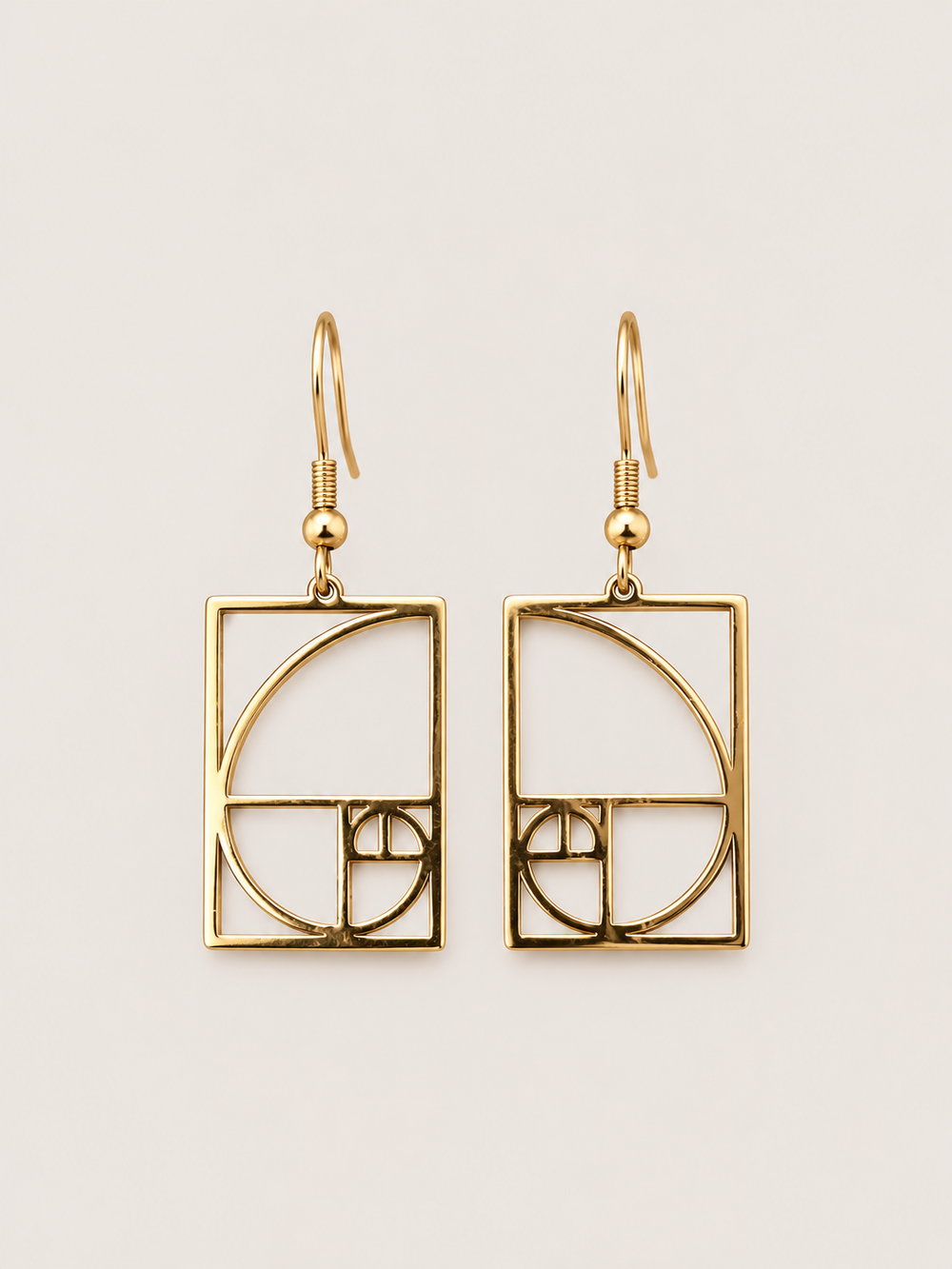 Gold Golden Ratio Spiral Drop Earrings shown on a warm neutral background