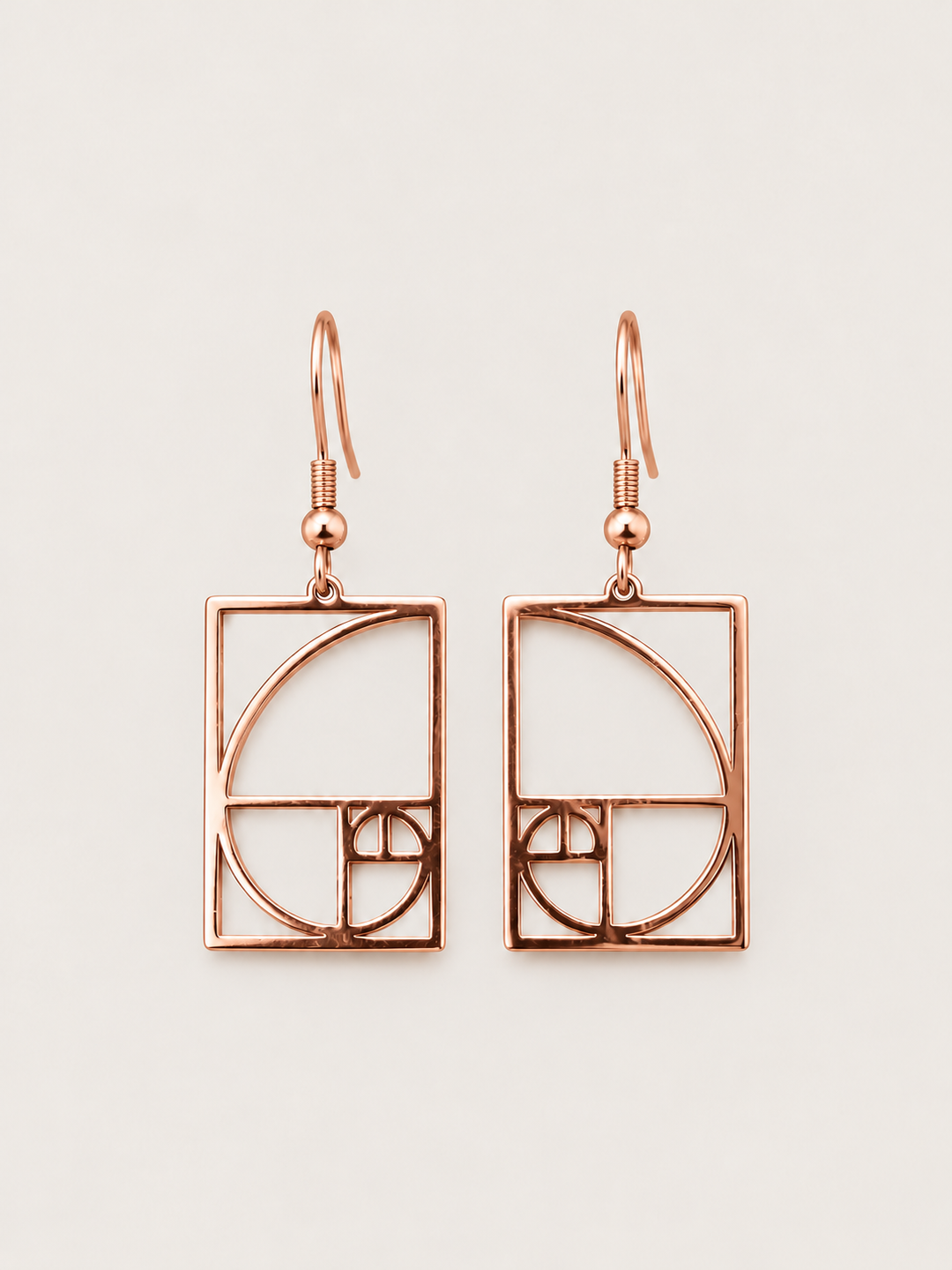 Rose gold Golden Ratio Spiral Drop Earrings shown on a warm neutral background