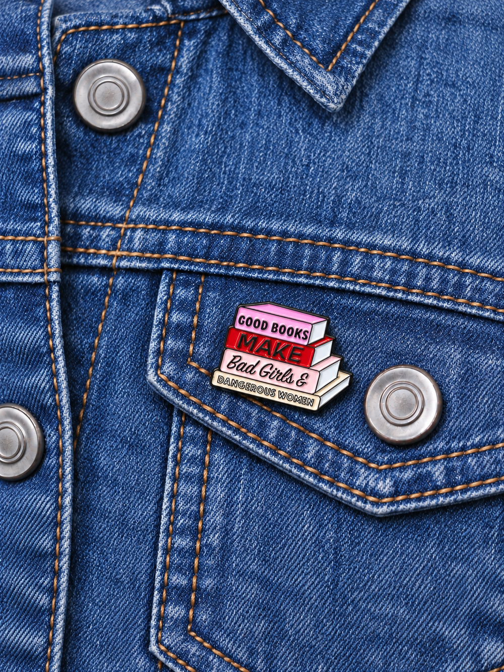 Good Books Make Dangerous Women Pin displayed on a stonewash denim jacket beside a metal button