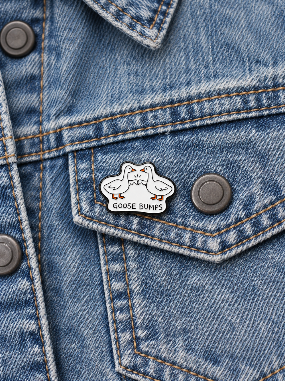 Goose Bumps Pin displayed on faded blue denim beside a gunmetal button