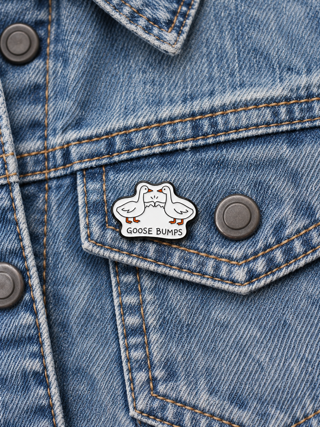 Goose Bumps Pin displayed on faded blue denim beside a gunmetal button