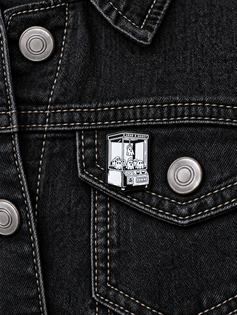 Grab a Ghost Claw Machine Pin displayed on black denim beside a metal button