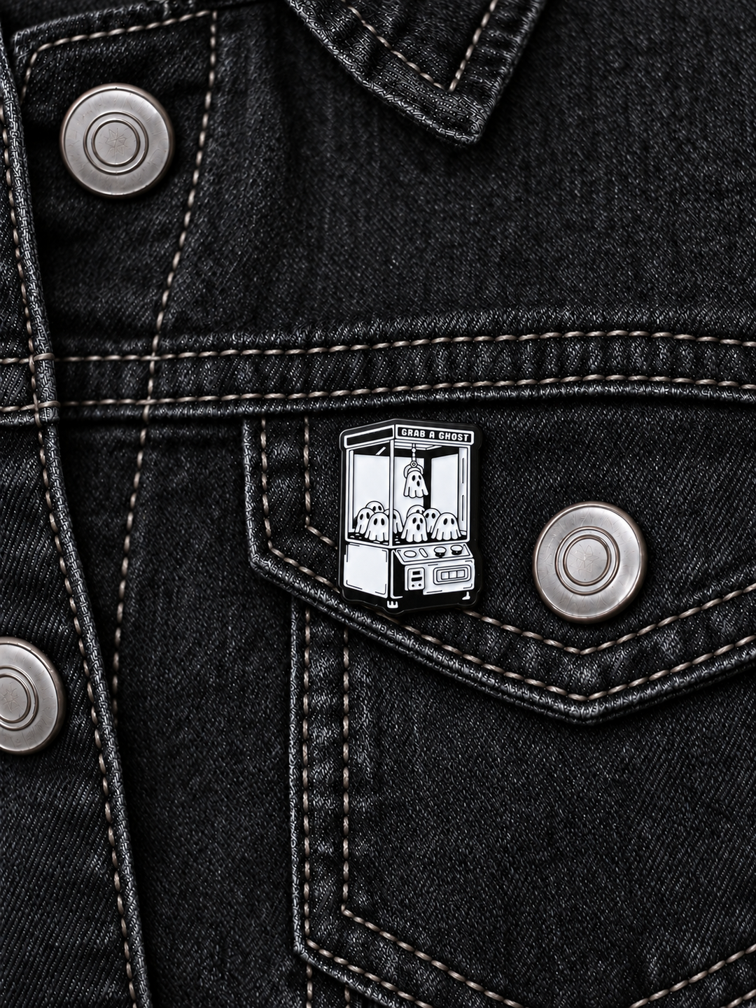 Grab a Ghost Claw Machine Pin displayed on black denim beside a metal button