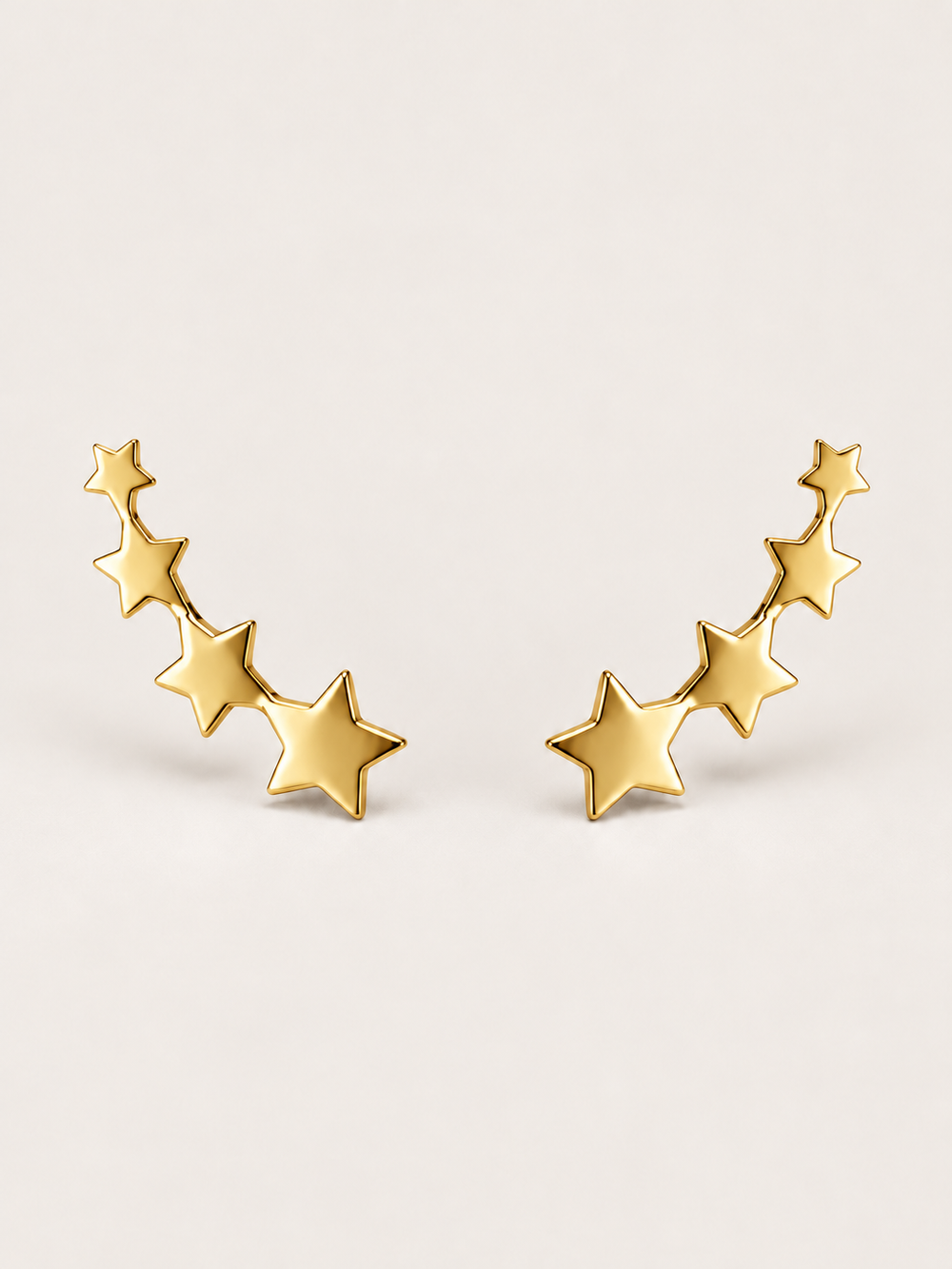 Gold Graduated Star Ear Crawler Earrings shown on a warm neutral background