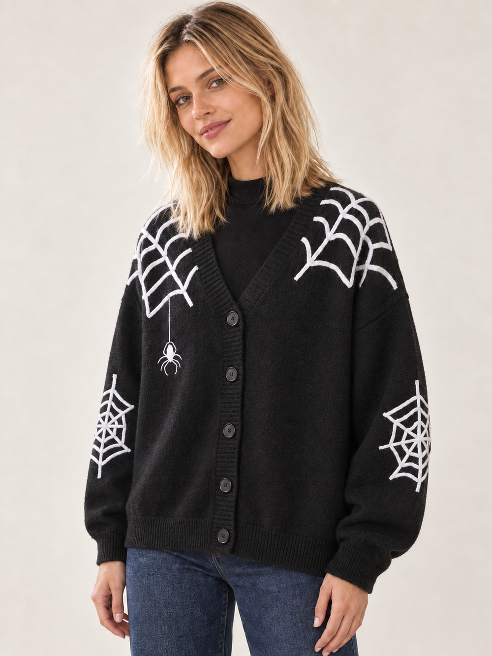 Angled view of black Halloween cardigan with white spiderwebs and spider applique