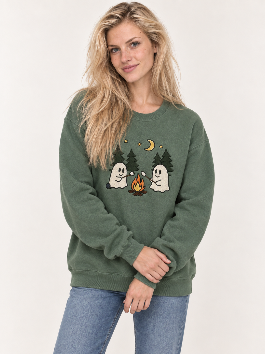Model wearing sage green embroidered ghost campfire sweatshirt, front view