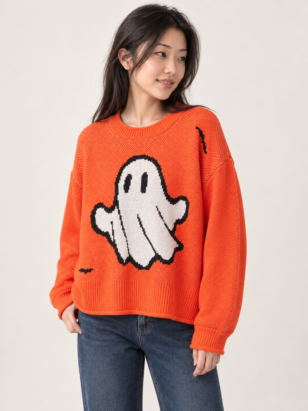 Angled view of oversized orange Halloween ghost sweater on model