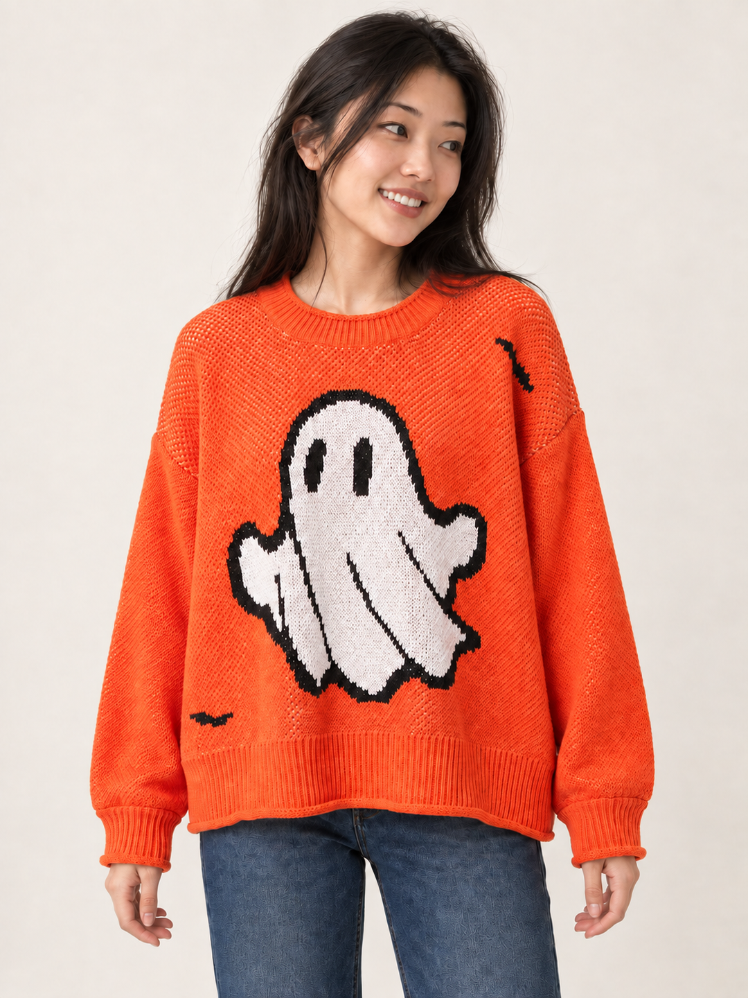 Front view of oversized orange Halloween ghost sweater on model