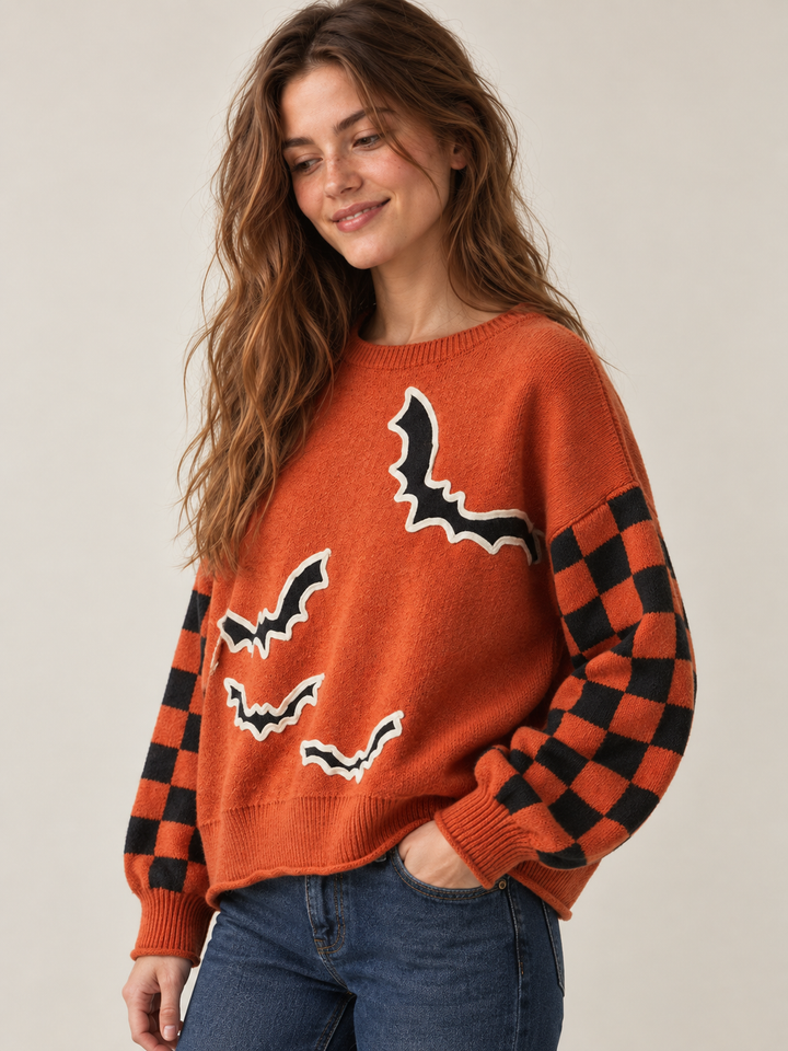 Orange bat applique sweater with checkered sleeves, angled view on model