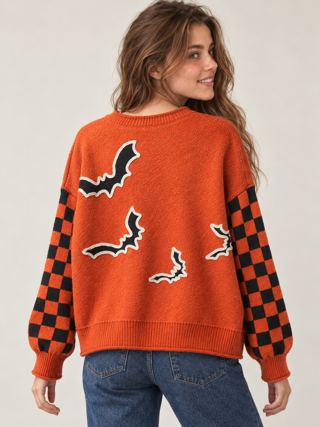Orange bat applique sweater with checkered sleeves, back view on model
