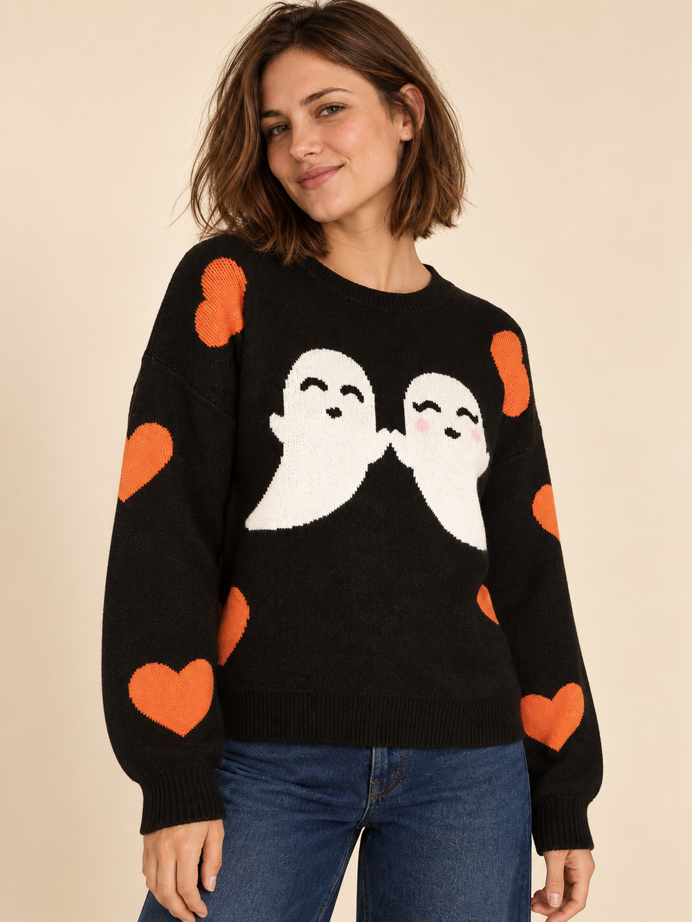 Black Halloween sweater with white ghosts and orange hearts, angled view on model