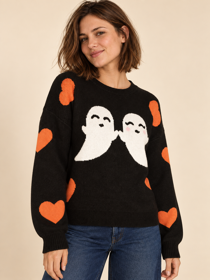 Black Halloween sweater with white ghosts and orange hearts, angled view on model