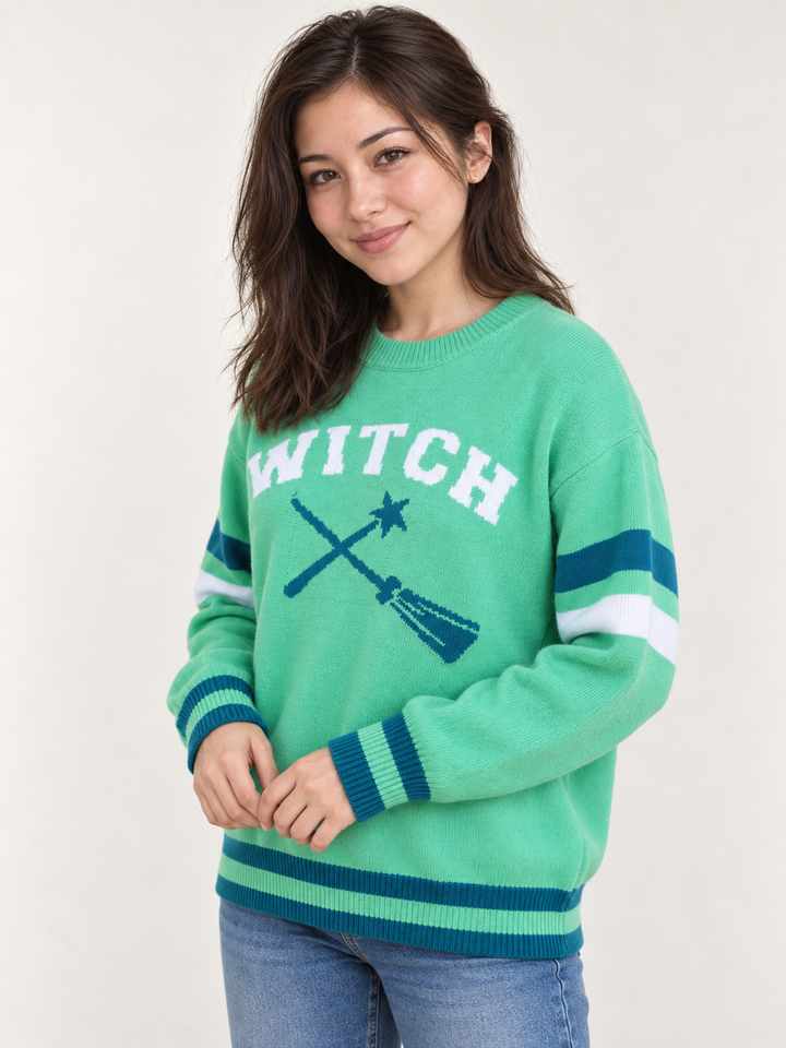 angle view of model wearing green Halloween WITCH sweater with teal and white striped details