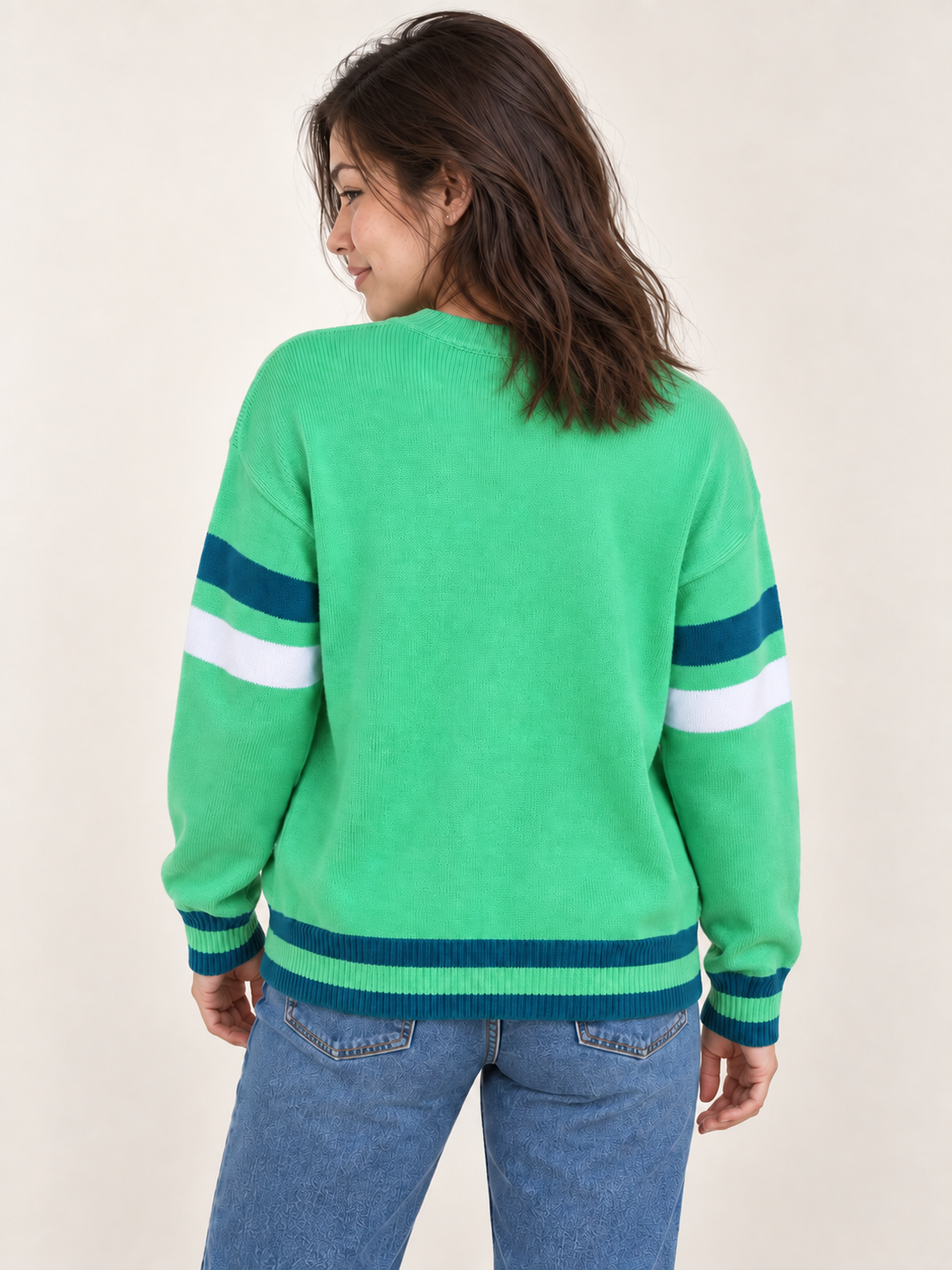 back view of model wearing green Halloween WITCH sweater with teal and white striped details