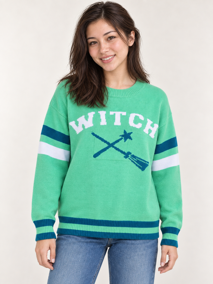 front view of model wearing green Halloween WITCH sweater with teal and white striped details
