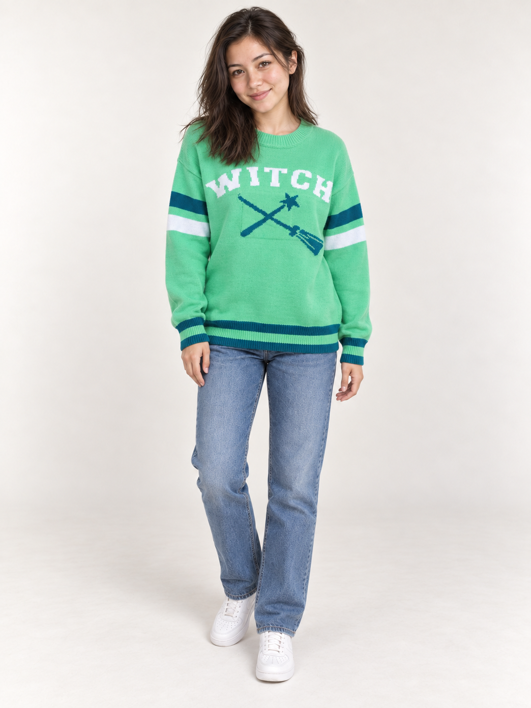 full-body view of model wearing green Halloween WITCH sweater with teal and white striped details