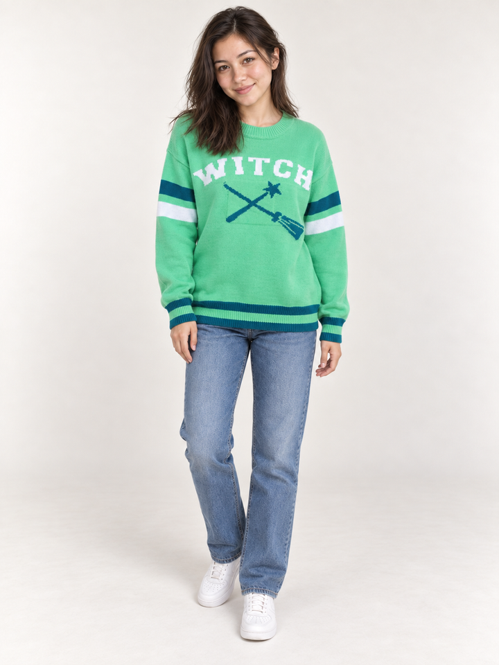 full-body view of model wearing green Halloween WITCH sweater with teal and white striped details