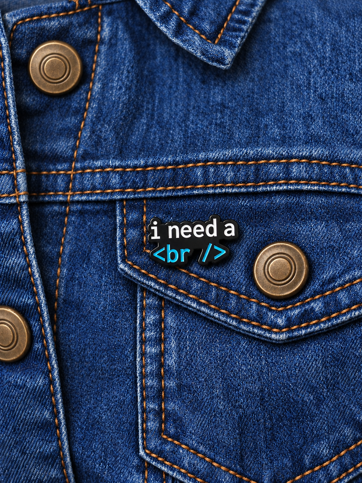 I Need a Break Code Pin displayed on a dark indigo denim jacket beside a metal button