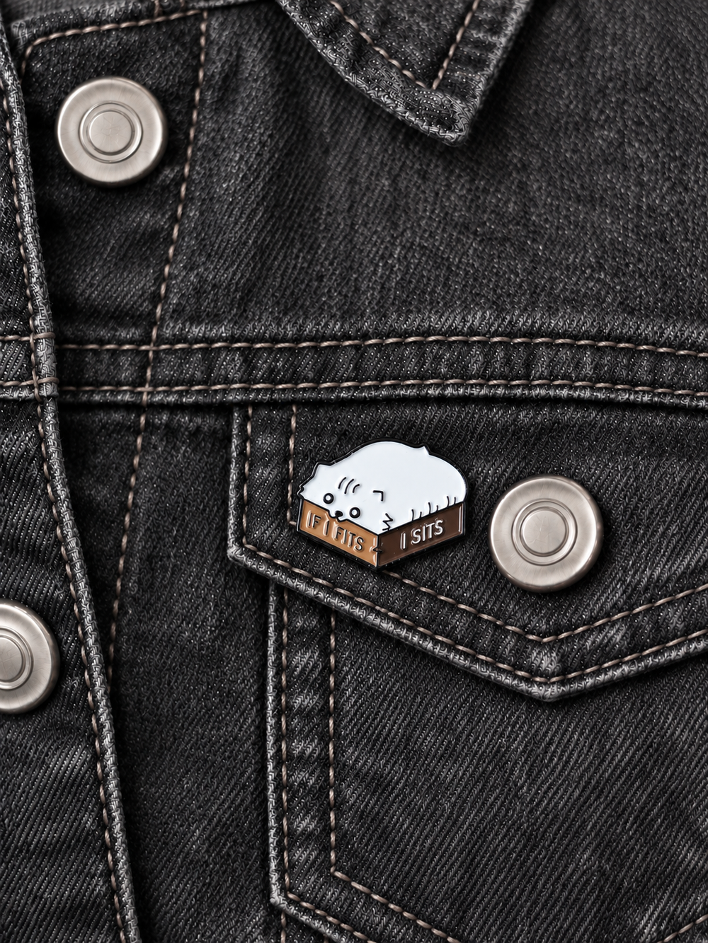 If Fits I Sits Cat Box Pin displayed on charcoal denim beside a metal button