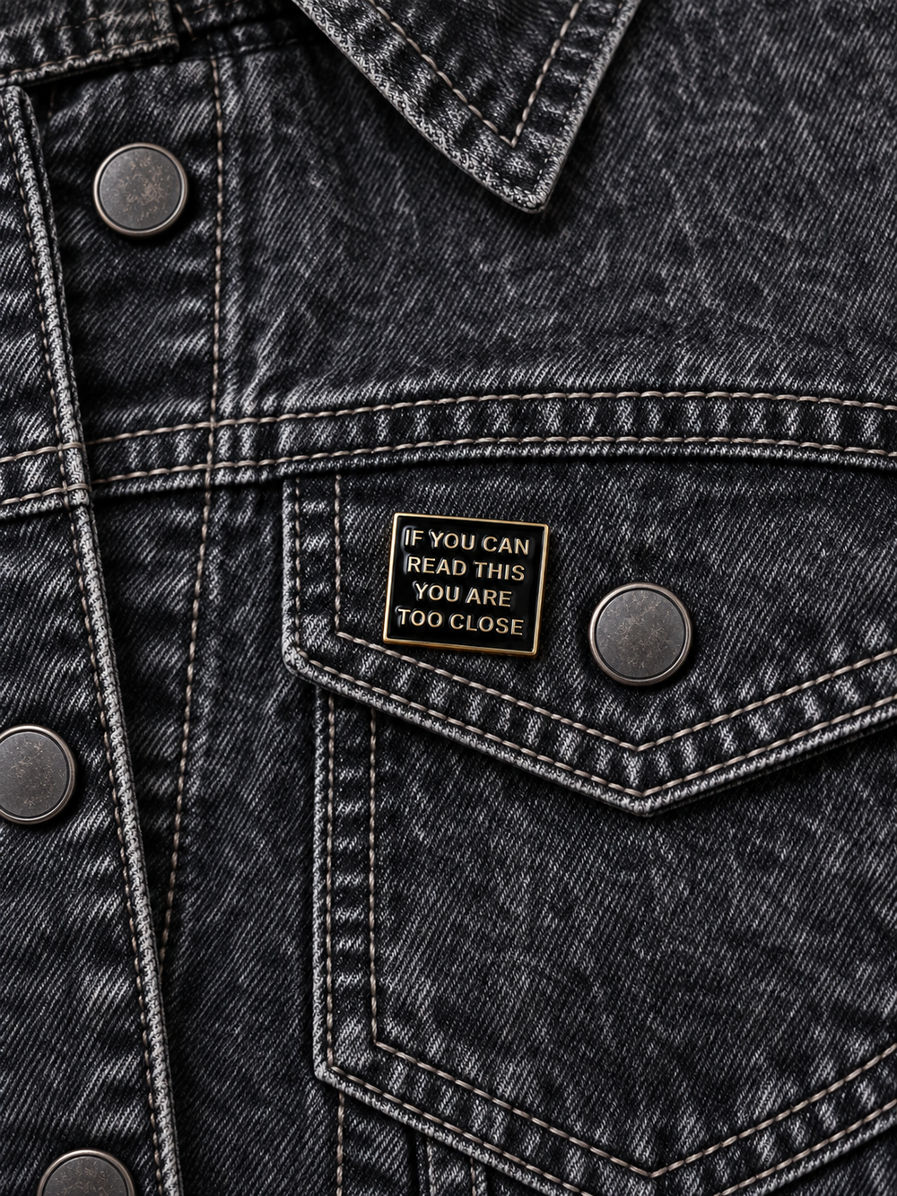 If You Can Read This Too Close Pin displayed on a black acid-wash denim jacket beside a metal button