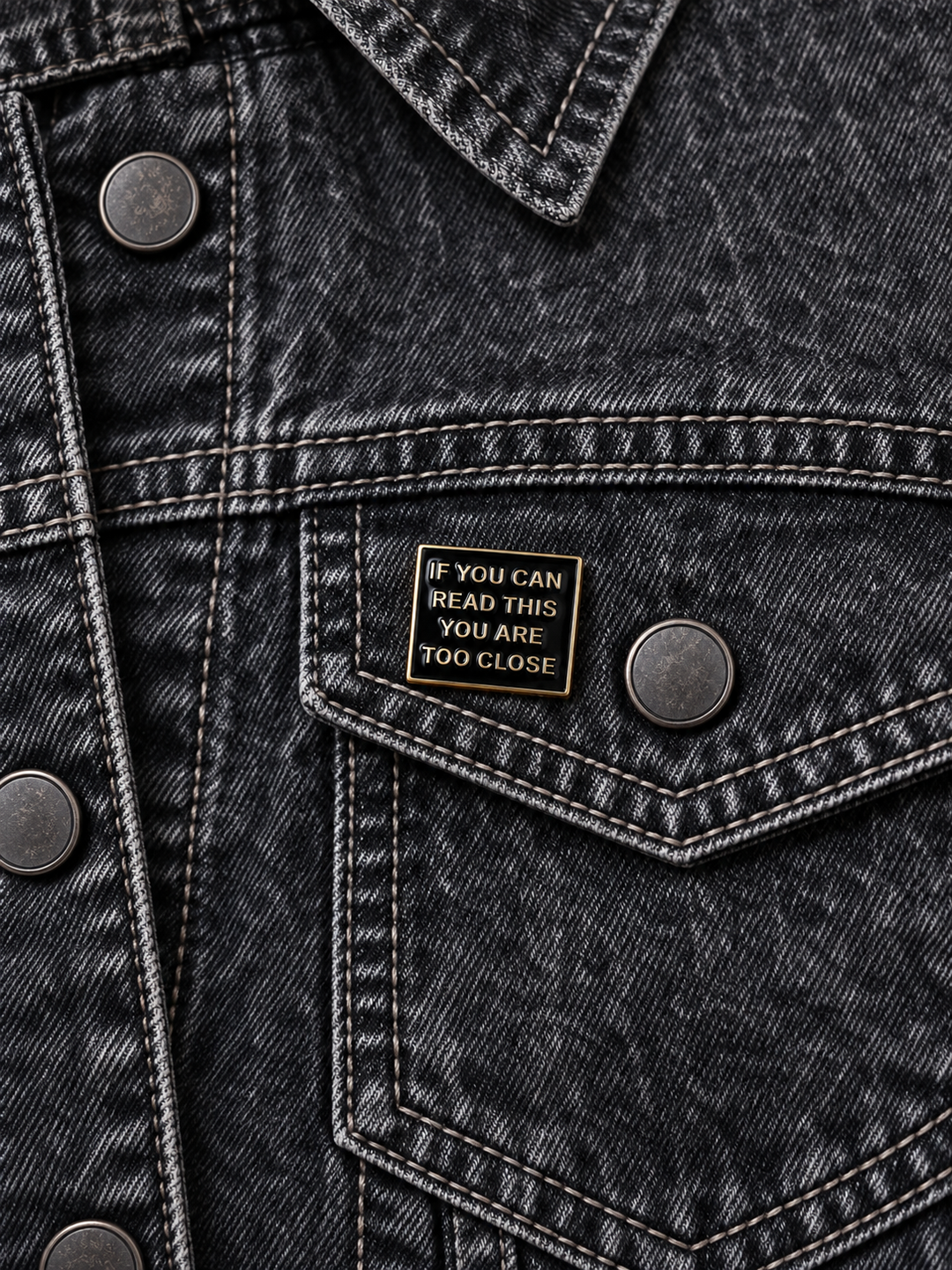 If You Can Read This Too Close Pin displayed on a black acid-wash denim jacket beside a metal button