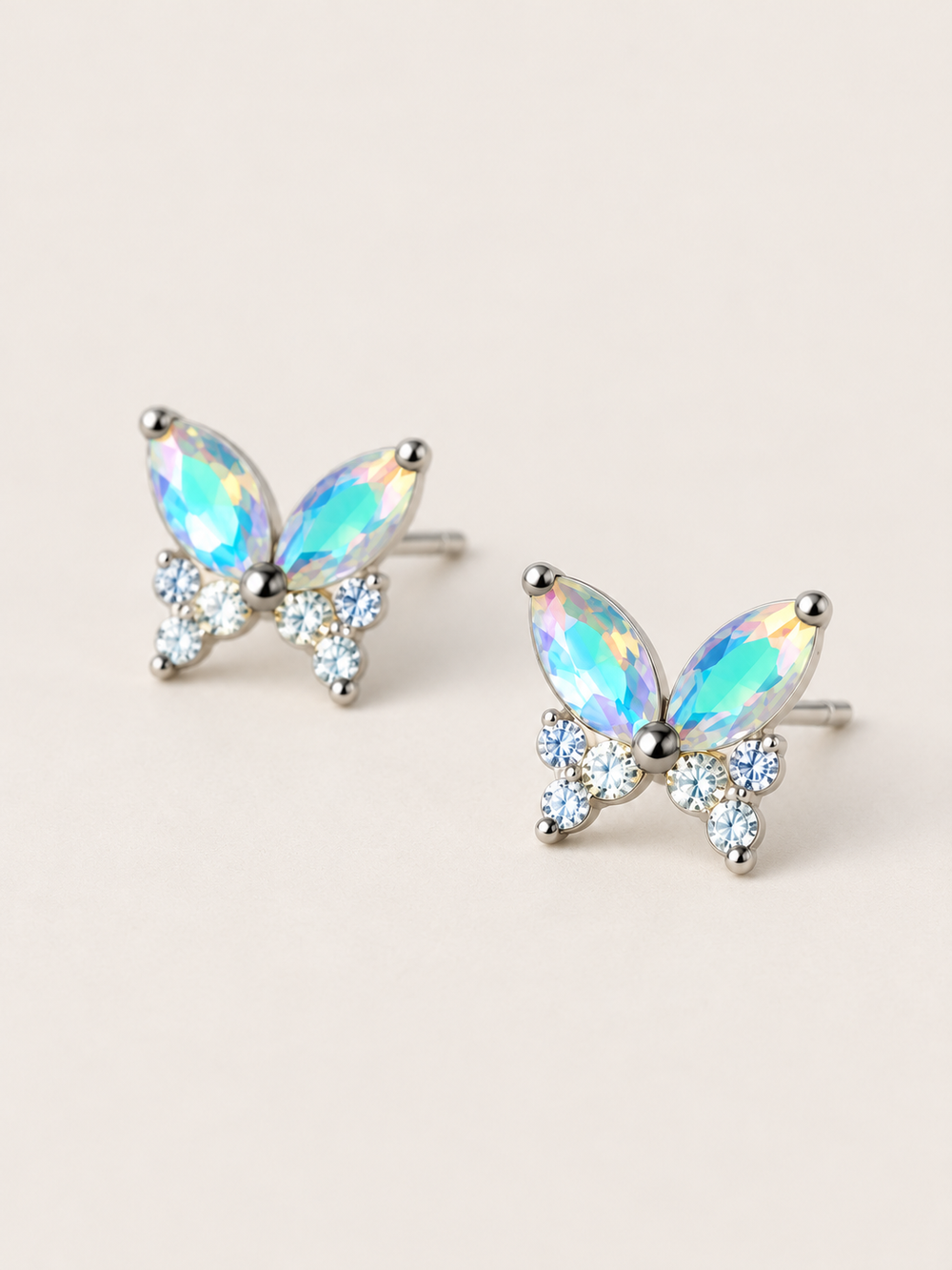 Iridescent Butterfly Stud Earrings shown angled on a warm neutral background