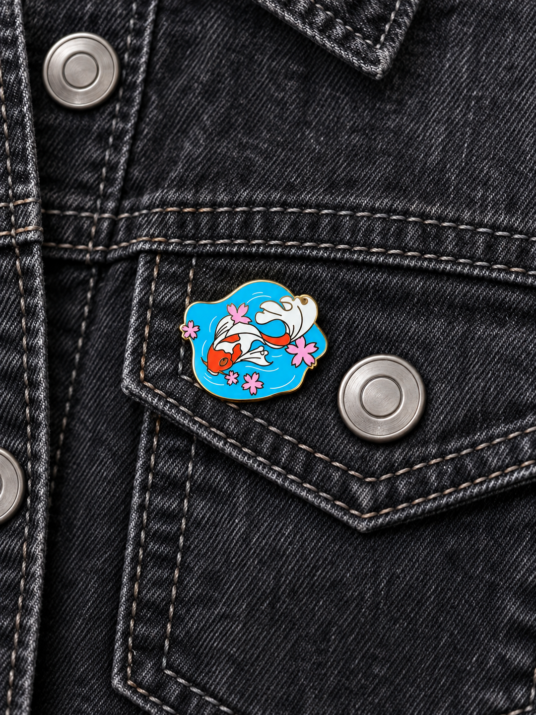 Koi Fish Pond Pin displayed on a charcoal denim jacket beside a metal button