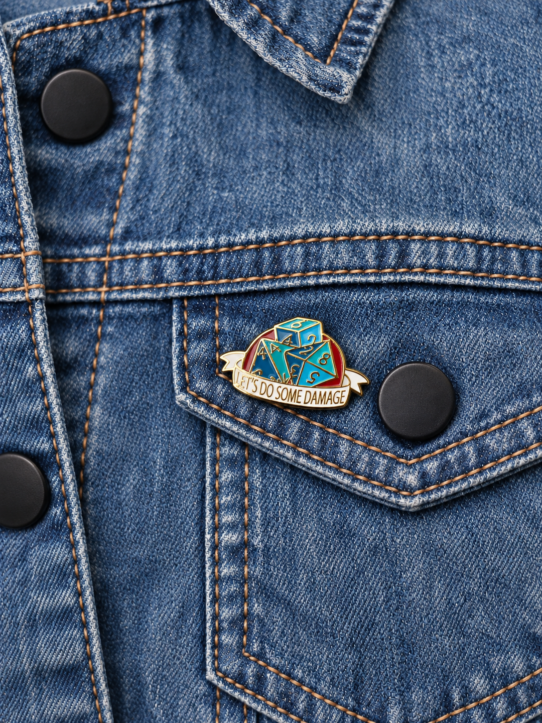 Let's Do Some Damage Dice Pin displayed on faded blue denim beside a black button