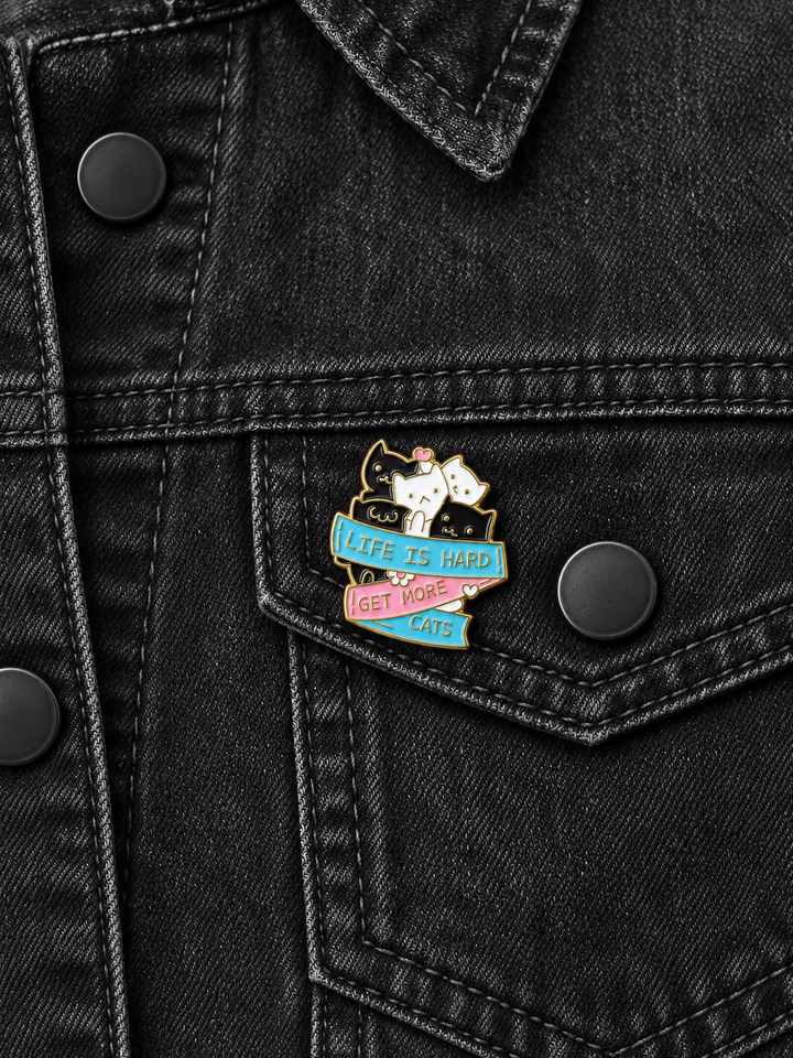 Life Is Hard Get More Cats Pin displayed on a blue denim jacket beside a metal button