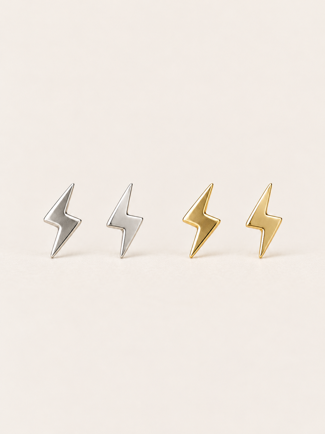 Silver and gold Lightning Bolt Earrings on a warm neutral background