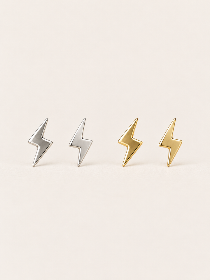 Silver and gold Lightning Bolt Earrings on a warm neutral background