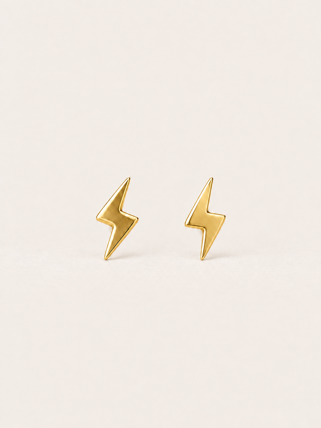 Gold Lightning Bolt Earrings on a warm neutral background