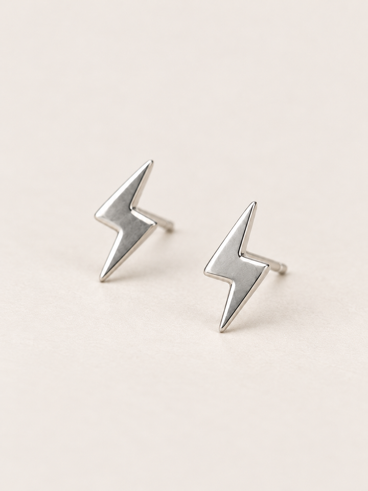 Silver Lightning Bolt Earrings angled on a warm neutral background